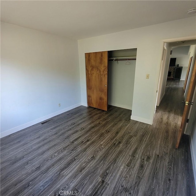 unfurnished bedroom featuring dark hardwood / wood-style flooring and a closet