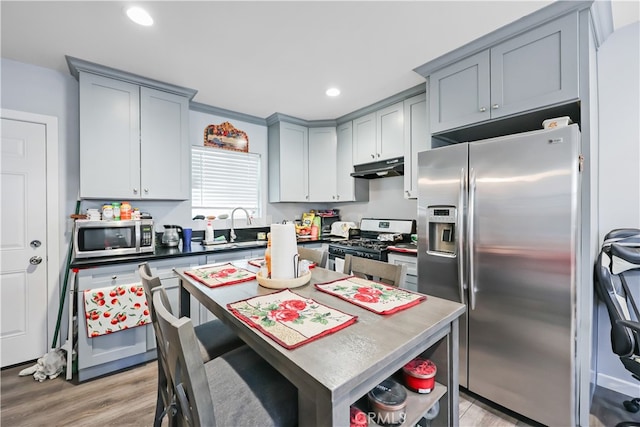 kitchen featuring light hardwood / wood-style floors, stainless steel appliances, a center island, gray cabinetry, and sink