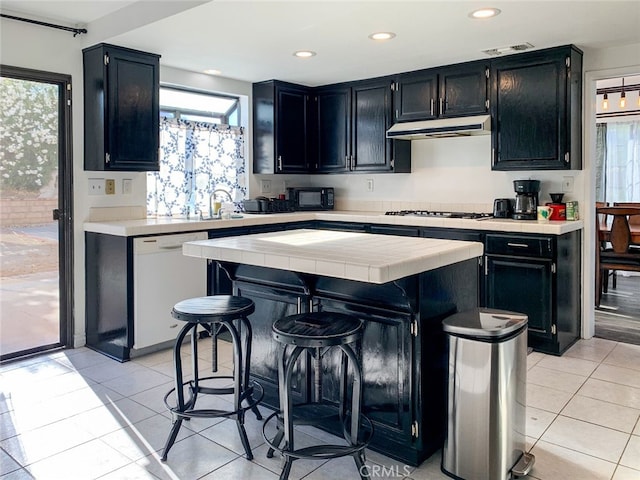 kitchen with a kitchen breakfast bar, a center island, a healthy amount of sunlight, and white appliances