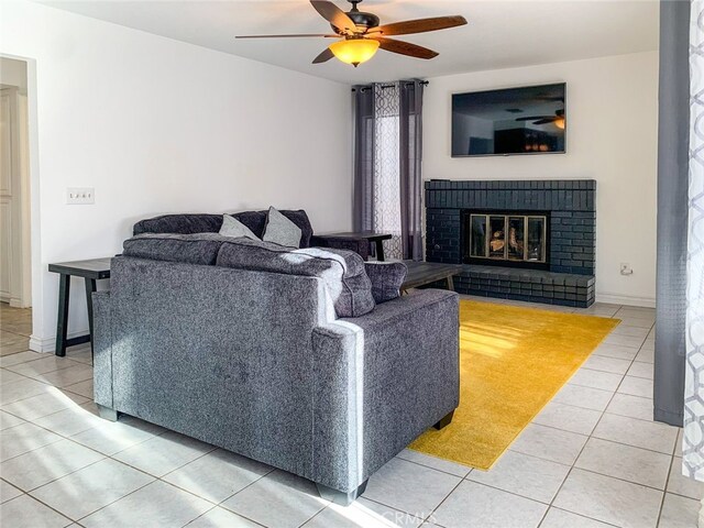 living room with ceiling fan, light tile patterned flooring, and a brick fireplace