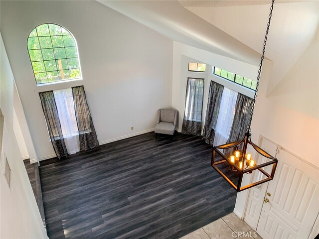 interior space featuring high vaulted ceiling, wood-type flooring, and a notable chandelier