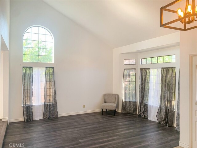 unfurnished room with dark hardwood / wood-style flooring, high vaulted ceiling, and an inviting chandelier