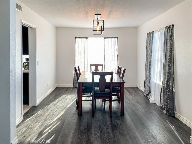 dining area with a textured ceiling, plenty of natural light, and dark wood-type flooring