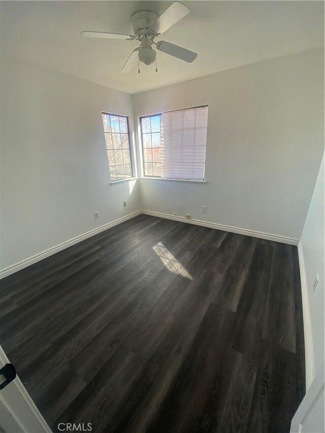 empty room featuring ceiling fan and dark wood-type flooring