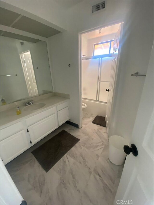 full bathroom with vanity, enclosed tub / shower combo, and toilet