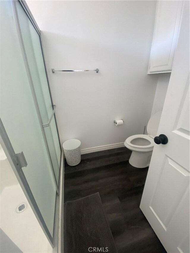 bathroom featuring hardwood / wood-style floors, toilet, and walk in shower