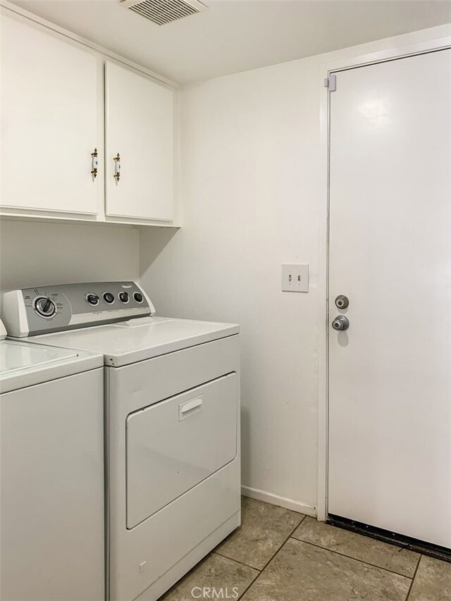 washroom featuring washing machine and dryer, light tile patterned floors, and cabinets