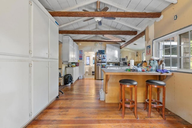 kitchen featuring ceiling fan, lofted ceiling with beams, wood ceiling, a kitchen breakfast bar, and white cabinets