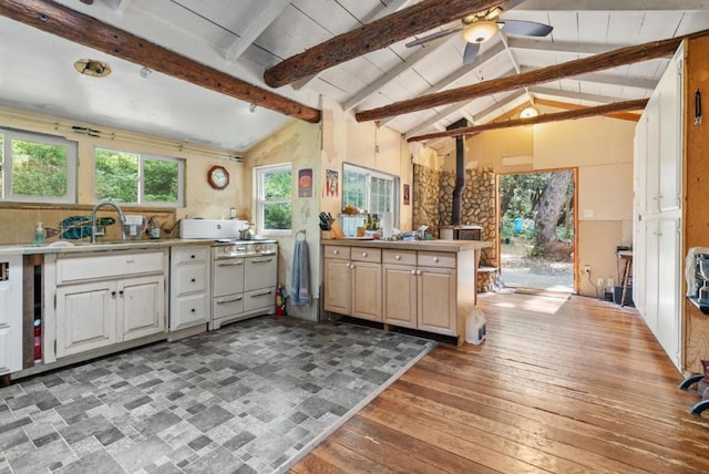 kitchen with ceiling fan, beam ceiling, a wood stove, and kitchen peninsula