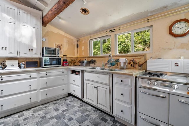 kitchen featuring sink, white cabinets, and vaulted ceiling with beams