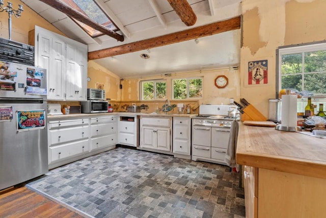 kitchen featuring white cabinetry, kitchen peninsula, appliances with stainless steel finishes, lofted ceiling with beams, and sink