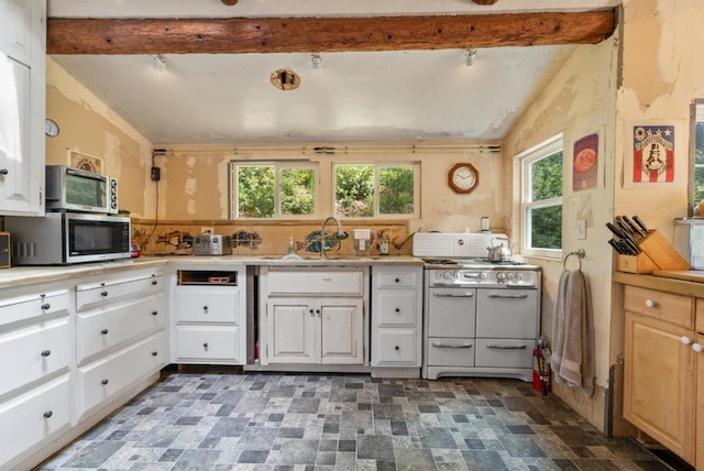 kitchen featuring white cabinetry, sink, range with two ovens, and vaulted ceiling with beams