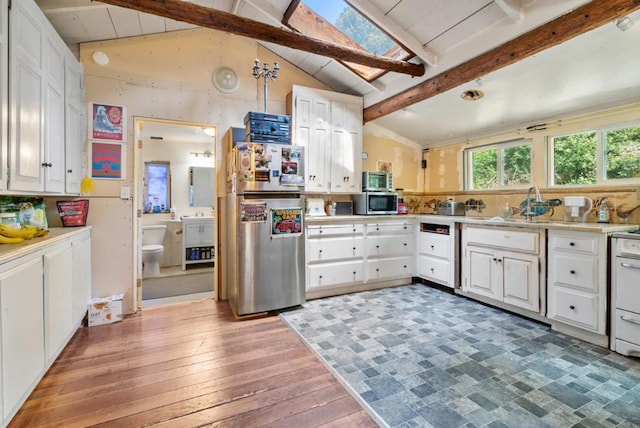 kitchen with white cabinets, lofted ceiling with skylight, dark hardwood / wood-style flooring, and stainless steel appliances