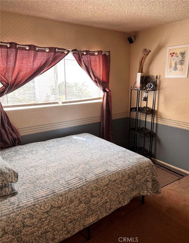 bedroom featuring multiple windows, carpet, and a textured ceiling