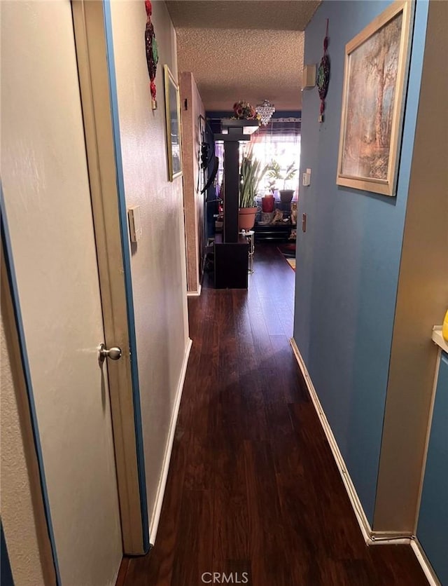 hallway with a textured ceiling and dark wood-type flooring