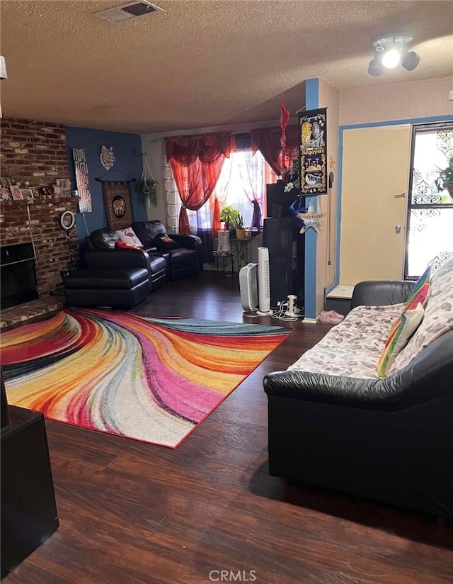 living room with dark hardwood / wood-style floors, a textured ceiling, and a brick fireplace