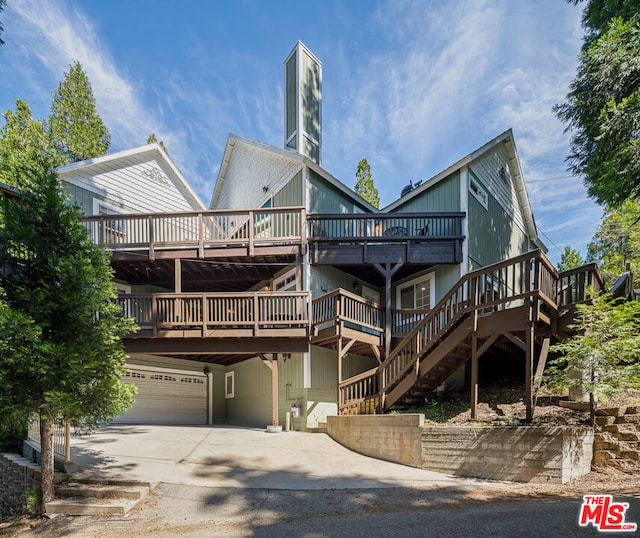 rear view of property with a garage and a deck