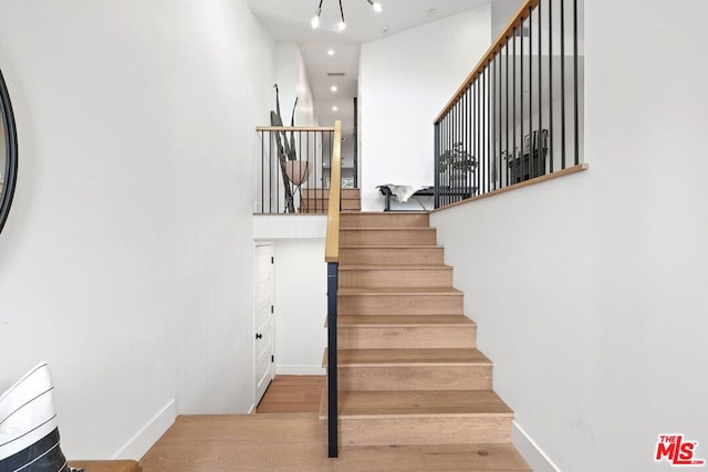 stairs with wood-type flooring and a notable chandelier