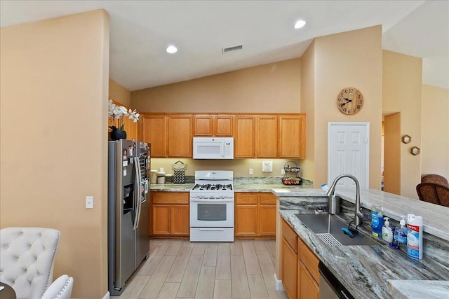 kitchen featuring light stone counters, stainless steel appliances, vaulted ceiling, sink, and light hardwood / wood-style floors