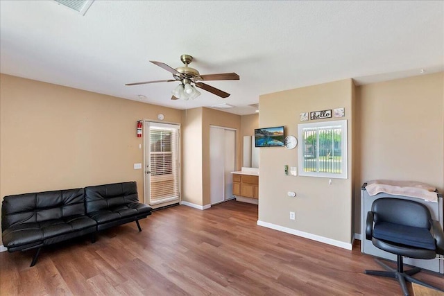 sitting room with ceiling fan and wood-type flooring