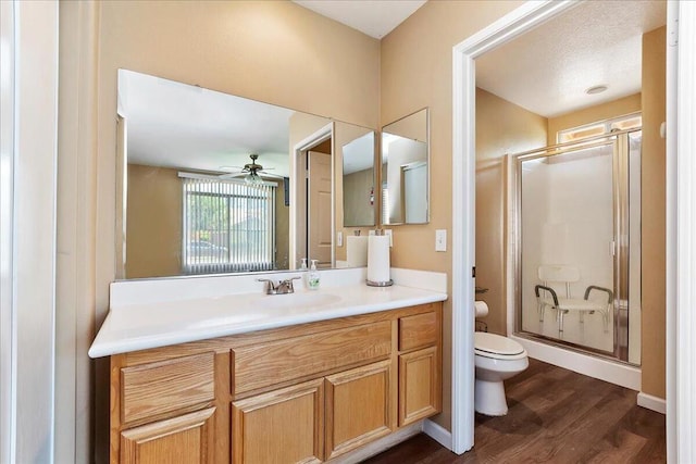 bathroom with ceiling fan, walk in shower, hardwood / wood-style floors, toilet, and vanity