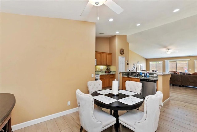 dining space featuring ceiling fan, light hardwood / wood-style floors, lofted ceiling, and sink