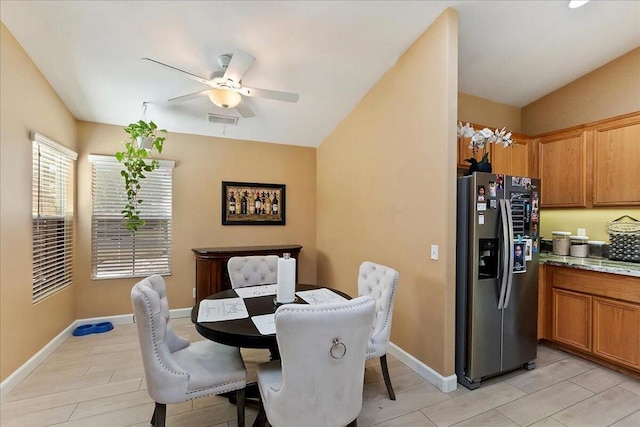 dining space featuring ceiling fan, light hardwood / wood-style flooring, and vaulted ceiling