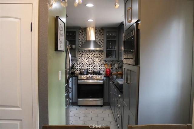 kitchen featuring stainless steel appliances, tasteful backsplash, wall chimney exhaust hood, and gray cabinetry