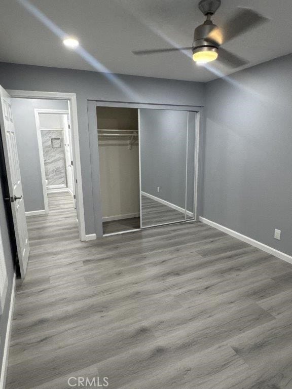 unfurnished bedroom featuring ceiling fan, a closet, and light hardwood / wood-style flooring