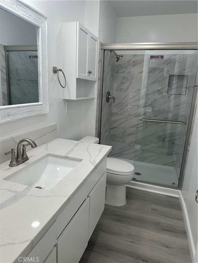 bathroom with toilet, walk in shower, wood-type flooring, and vanity