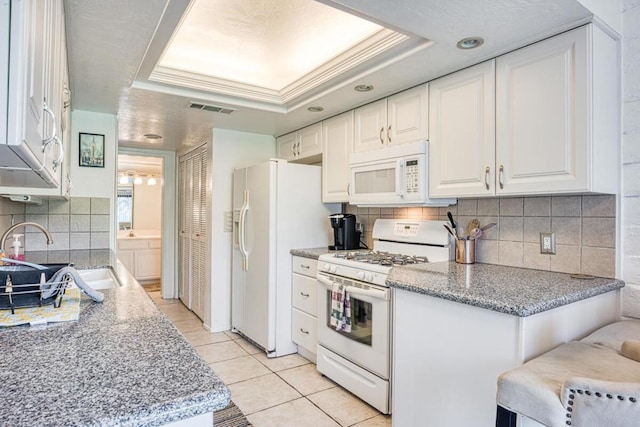 kitchen featuring white cabinetry, white appliances, sink, and a tray ceiling