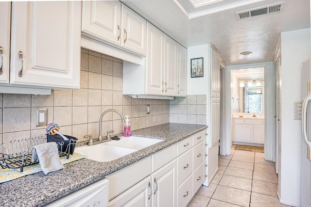 kitchen featuring light stone countertops, sink, white cabinets, and light tile patterned floors