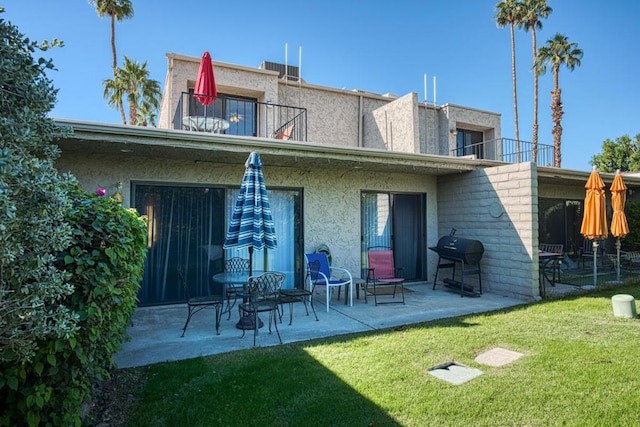 back of property featuring a yard, a patio area, and a balcony