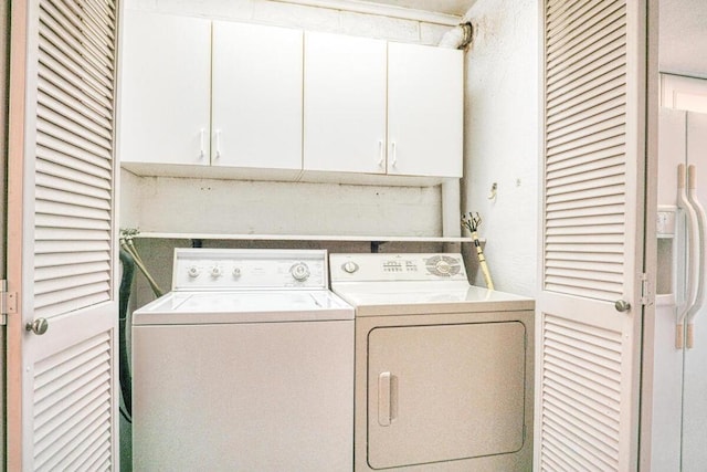 laundry room featuring separate washer and dryer and cabinets