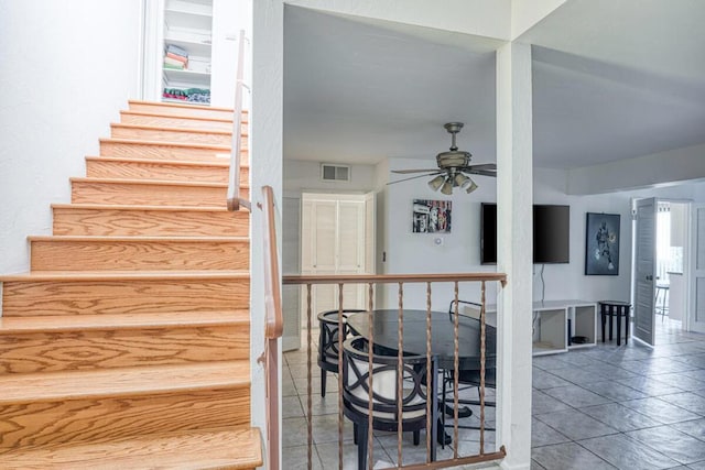 stairway featuring ceiling fan