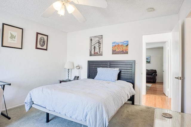 carpeted bedroom featuring ceiling fan and a textured ceiling