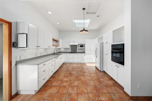 kitchen with a skylight, decorative light fixtures, sink, white cabinets, and white appliances