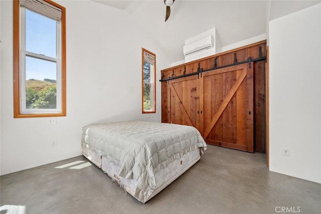 bedroom with ceiling fan, a wall mounted air conditioner, a barn door, and concrete floors