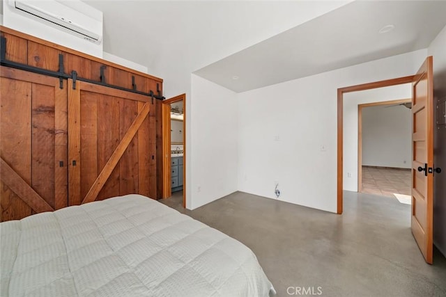 bedroom with concrete flooring, a barn door, and a wall mounted AC