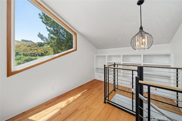 bonus room featuring hardwood / wood-style flooring, lofted ceiling, and a chandelier