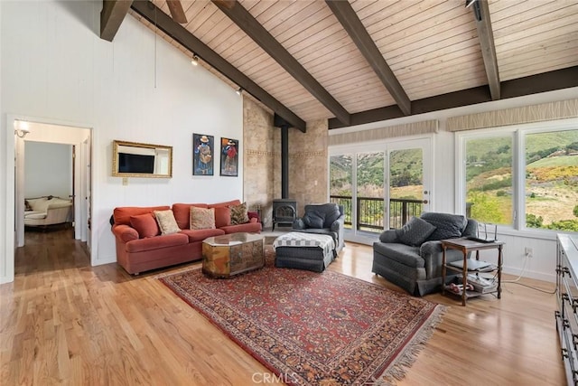 living room with high vaulted ceiling, light hardwood / wood-style floors, wooden ceiling, beamed ceiling, and a wood stove