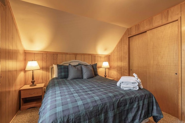 bedroom with wooden walls, lofted ceiling, a closet, and carpet flooring