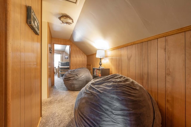 bedroom featuring wooden walls, vaulted ceiling, and carpet flooring