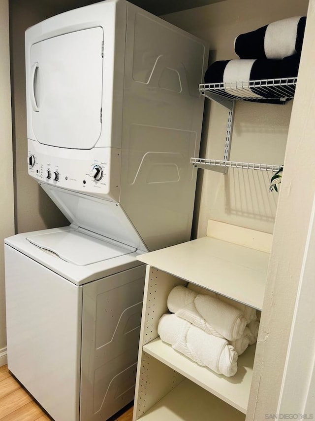 laundry area featuring hardwood / wood-style floors and stacked washer / dryer