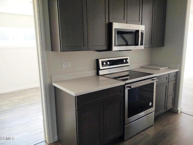 kitchen with appliances with stainless steel finishes and hardwood / wood-style floors