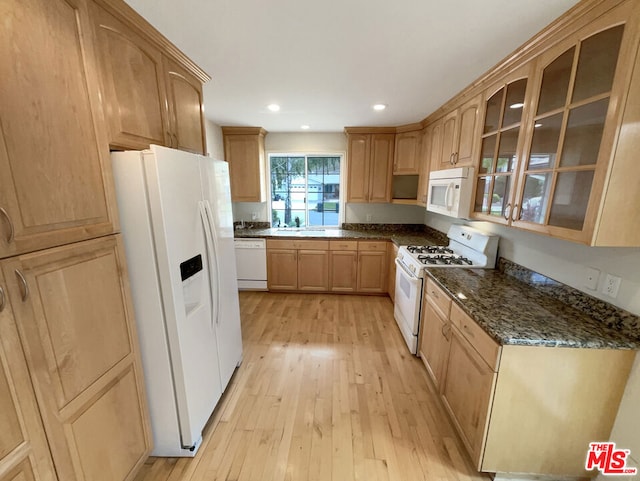 kitchen featuring light brown cabinets, white appliances, light hardwood / wood-style floors, and dark stone countertops