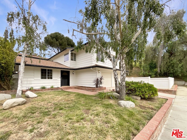 view of property with a garage and a front lawn