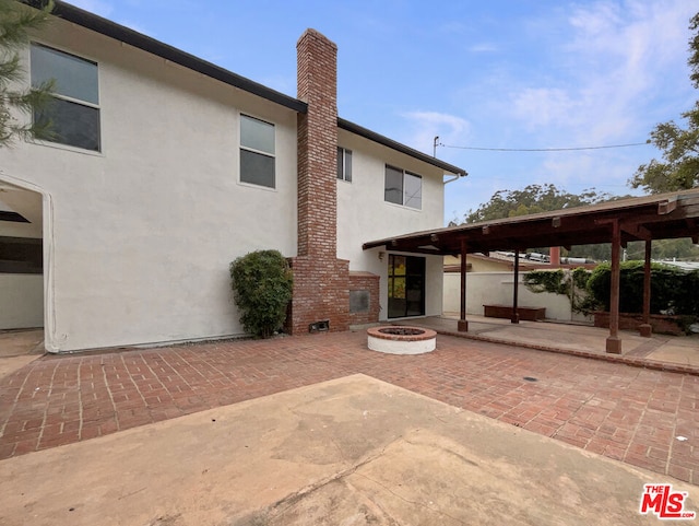 rear view of property featuring a patio and a fire pit