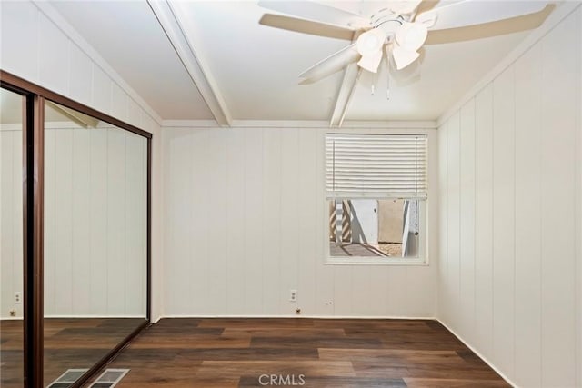 unfurnished bedroom featuring dark hardwood / wood-style flooring, a closet, wood walls, and ceiling fan