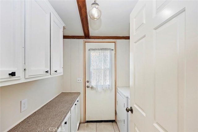 kitchen featuring white cabinets, beam ceiling, washer / dryer, and light tile patterned floors